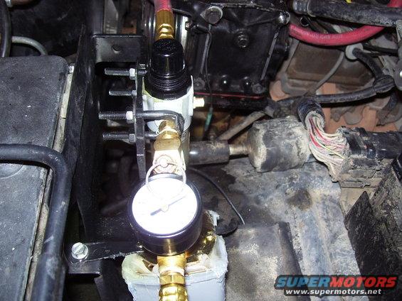 Air pressure gauge and regulator assembly mounted in engine bay. Wires and engine components visible