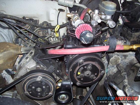 Engine bay with AC compressor, hoses, and belts visible