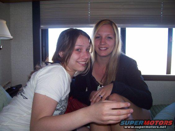 Two young women smiling indoors, with blinds and a window behind them. A watermark says 'SUPERMOTORS'