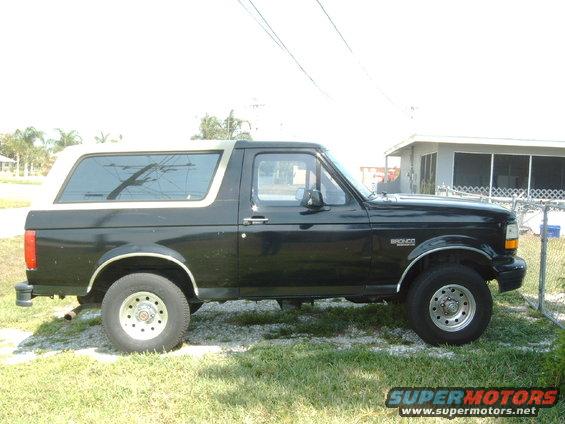 Side view of a black 1994 Ford Bronco with a tan top parked on grass
