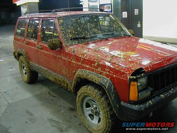Mud-covered red 1995 Jeep Cherokee, 3/4 front view