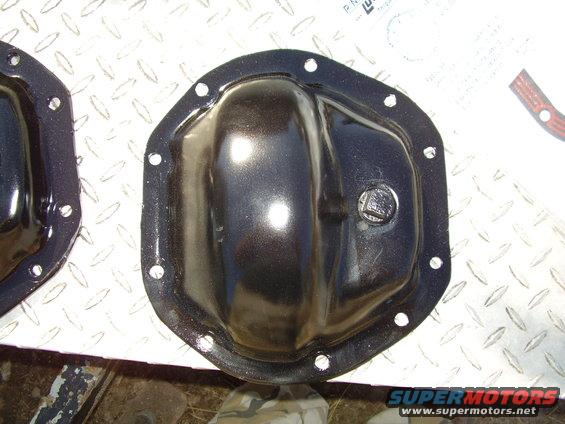 Two black differential covers on a diamond plate surface, one in focus with a bolt head visible