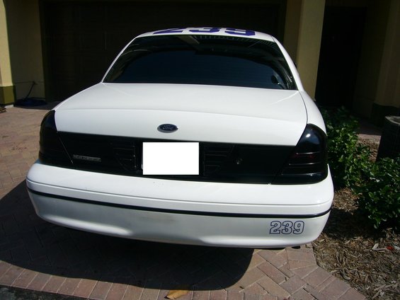 Rear view of a white sedan with tinted taillights and black grille. Blue numbers '239' are on the bumper and roof