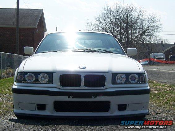 front view of a white BMW E36 sedan with halo headlights