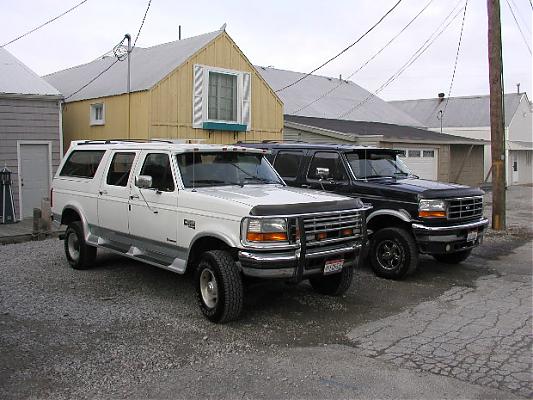 White 1995 Ford C-350 Centurion Conversions SUV parked next to a black one