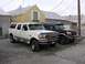1995 Ford C-350 (Centurion Conversions) - Two Ford C-350 Centurion Conversions SUVs, one white and one black, are parked in front of buildings.