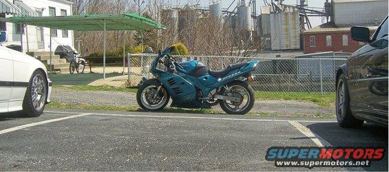 Teal motorcycle parked next to a white BMW E36 coupe