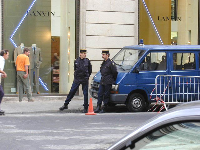 Blue van with police officers standing nearby, Lanvin store in background