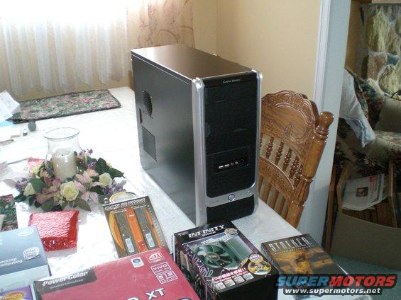Computer tower, RAM sticks, fan, and game cases on a table with a floral centerpiece