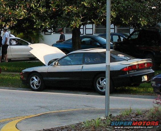 Two-tone silver and black Ford Probe coupe parked on a street, hood up, side view