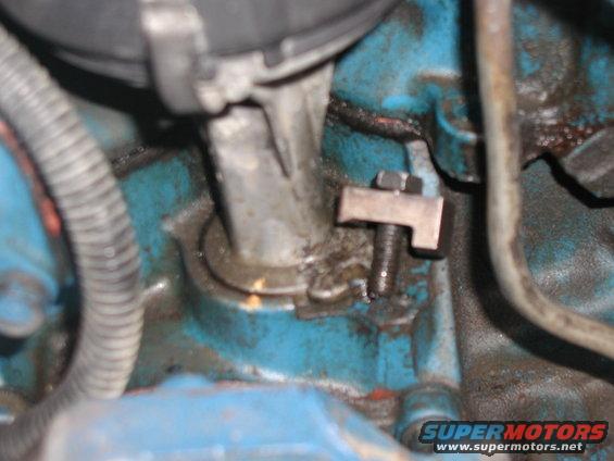 Close-up of a metal bracket bolted to a blue engine block