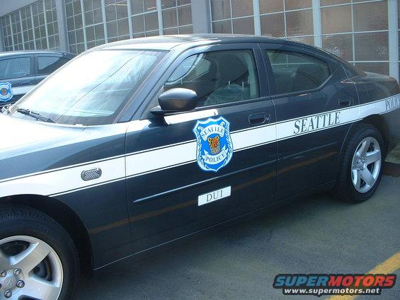 Dark blue Seattle Police car with white stripe and "SEATTLE POLICE" text, side view