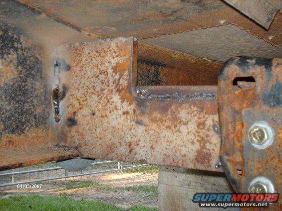 Close-up of heavily rusted metal frame with visible welds and bolts, suggesting structural modification