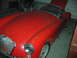 1959 MG A - A red 1959 MG A sports car sits in a garage with its hood up, showing some dust and wear.
