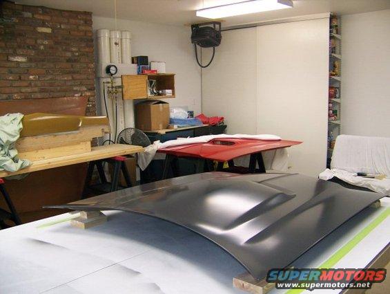 Dark grey car hood with two raised vents, resting on a white surface