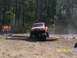 1989 Ford Bronco - An orange off-road SUV navigates an obstacle course in a wooded area.