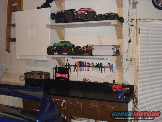 Shelves with remote control monster trucks and a workbench with tools