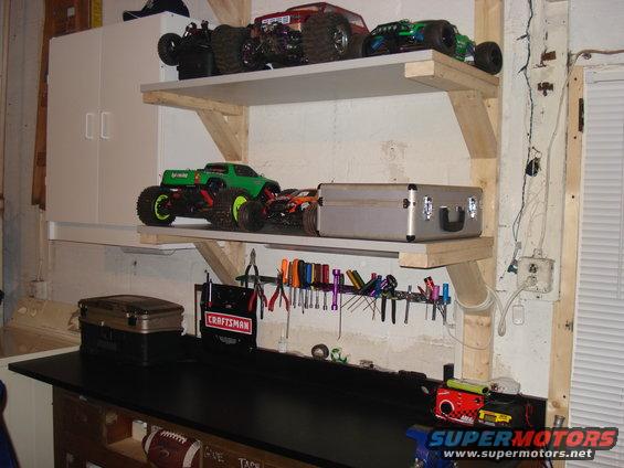 Shelves with remote control monster trucks, a toolbox, and tools on a workbench