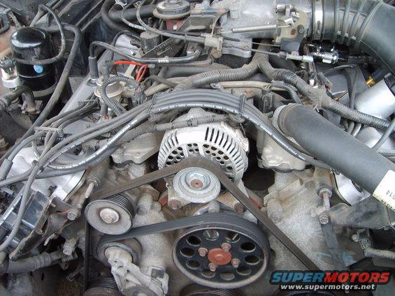 Close-up of a car engine bay showing the alternator, serpentine belt, and pulleys
