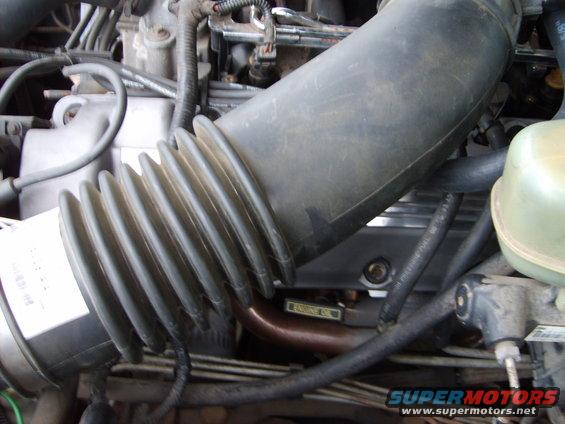 Close-up of engine bay showing air intake hose and engine components. Text 'ENGINE OIL' is visible