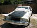 1985 Ford Crown Victoria LTD - A car is being prepped for painting, with the hood covered in primer and the fenders masked off.