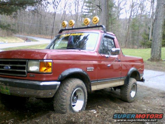 1989 Ford Bronco, red, with roof rack and four smiley face lights
