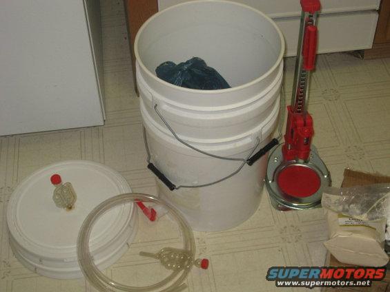 Bucket, lid with airlock, tubing, and bottle capper on floor
