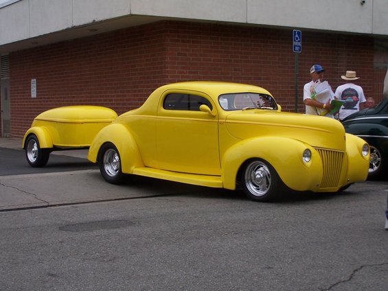 Yellow 1940s coupe with a custom trailer, viewed from the front three-quarter angle