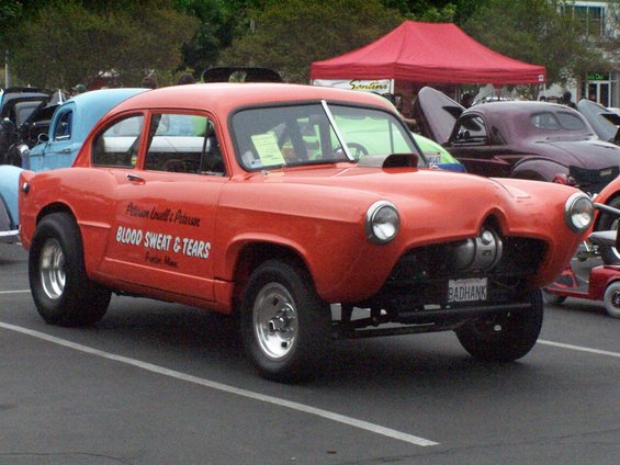 Orange custom car with "BADHANK" license plate and "BLOOD SWEAT & TEARS" text on the side