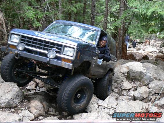 Blue Ford Bronco II navigating a rocky trail with a driver visible