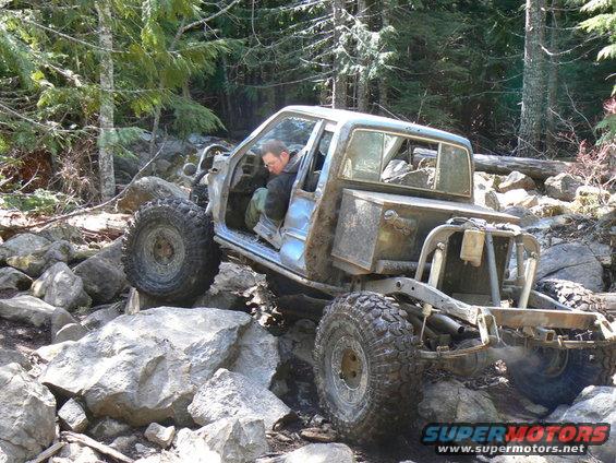 Light blue off-road vehicle with exposed frame and large tires navigating rocky terrain