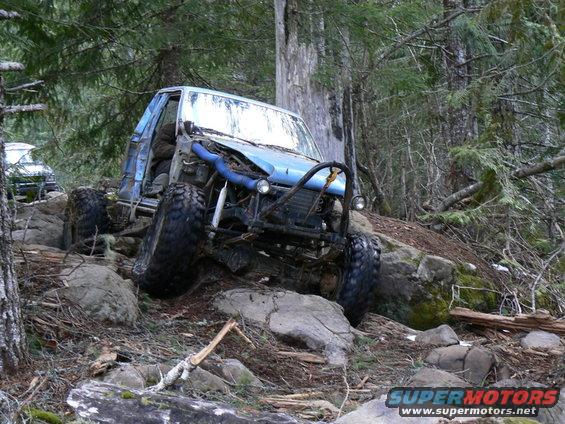 Modified off-road vehicle navigating a steep, rocky trail with another vehicle visible behind it