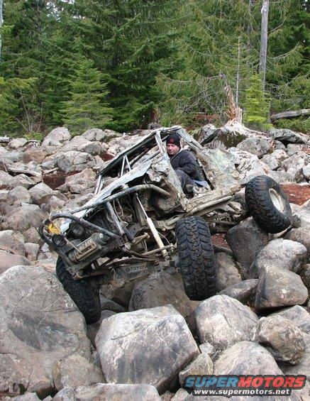 Heavily modified off-road vehicle with a roll cage, stuck on large rocks