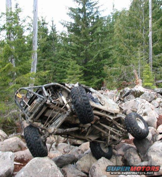 Off-road buggy tilted on large rocks in a forest