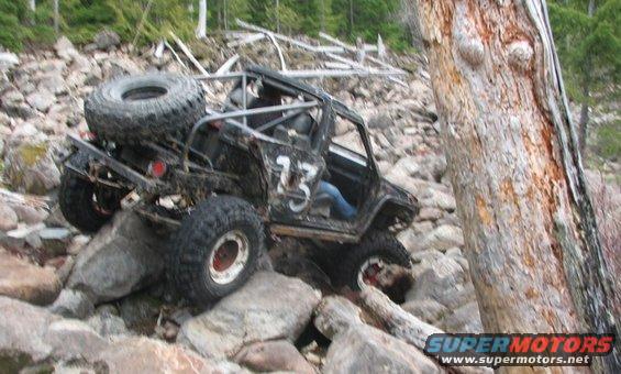 Modified off-road vehicle with roll cage and spare tire on rocks
