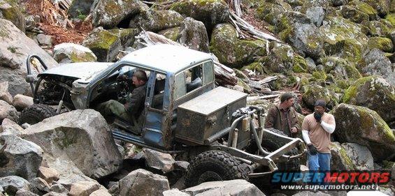 Off-road vehicle with custom modifications stuck between large rocks