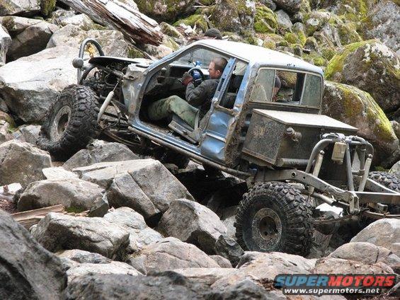 Modified pickup truck with doors removed navigating a rocky terrain