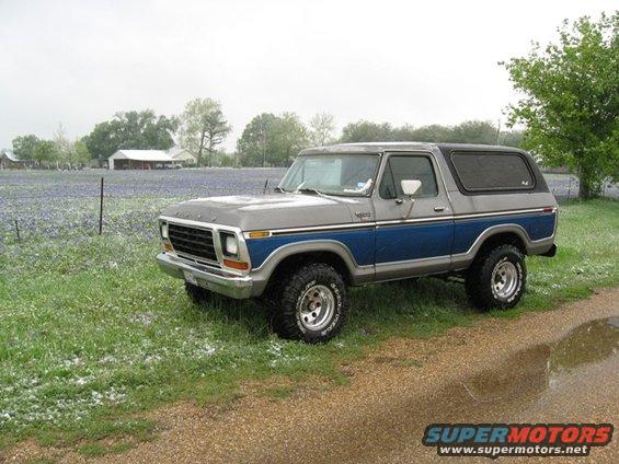 1979 Ford Bronco parked on a gravel road next to a field of bluebonnets