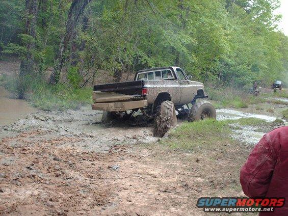 Muddy lifted pickup truck stuck in a muddy off-road course