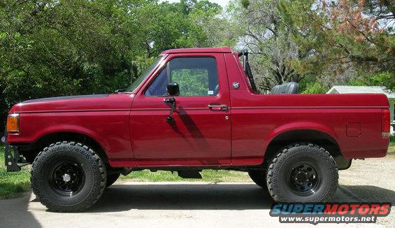 Red SUV with black wheels and off-road tires, side view
