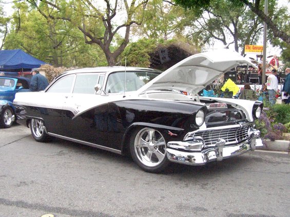 Black and white 1956 Ford Fairlane Crown Victoria parked with hood open. Another car is visible to the left