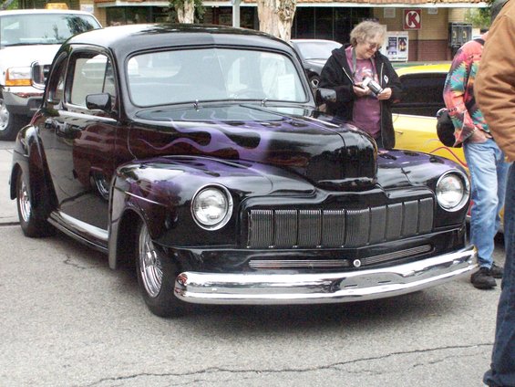 Black coupe with purple flames, chrome bumper, and custom grille, viewed from the front