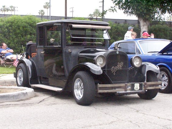 Black vintage Dodge car with Route 66 plate, parked next to a blue car