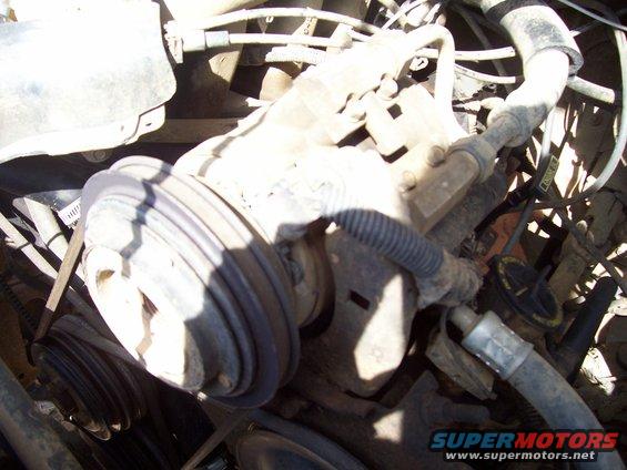 Close-up of engine pulleys, belts, and hoses in a vehicle
