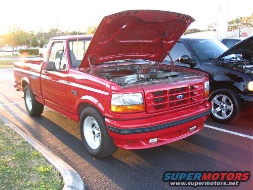 Red 1994 Ford F-150 pickup truck with hood open, parked next to a black truck