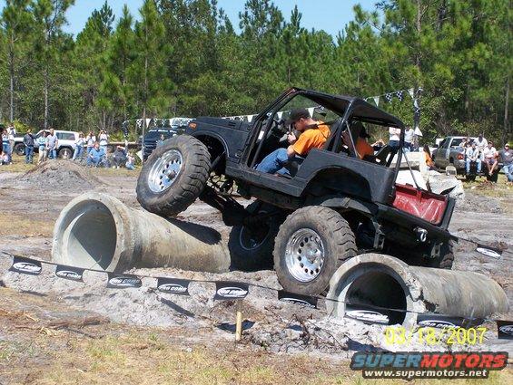 Black off-road SUV with large tires navigating concrete pipes, driver visible