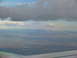 1995 Ford C-350 (Centurion Conversions) - Looking down from an airplane at clouds, mountains, and a distant town.