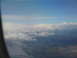 1995 Ford C-350 (Centurion Conversions) - View from an airplane window shows clouds obscuring a mountainous landscape below.