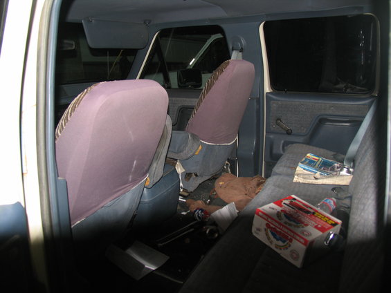 Interior of a 1995 Ford C-350 (Centurion Conversions) showing front and rear seats, door panels, and floor debris