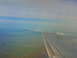 1995 Ford C-350 (Centurion Conversions) - View from an airplane window shows a wing and a distant mountain range under a hazy sky.